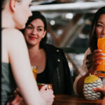 photo of three young women sipping cocktails and smiling